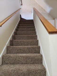 a carpeted staircase with a wooden railing and carpeted stairs